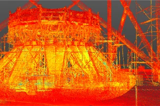Nube de puntos 3D escaneada de una gran estructura industrial en el NAICM Texcoco, representada en tonos rojos, naranjas y amarillos, mostrando andamios detallados y componentes cilíndricos sobre un fondo oscuro.