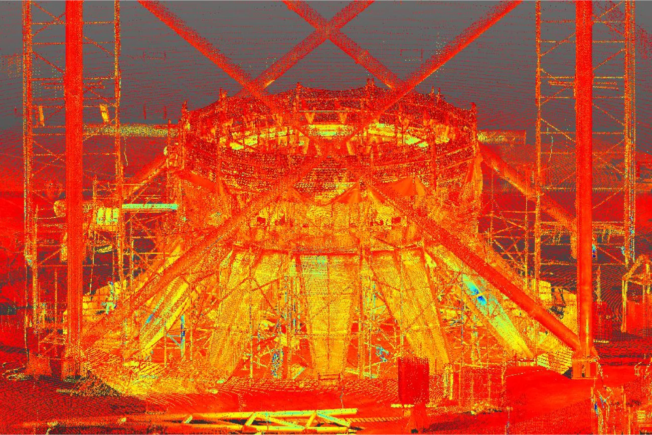 Una colorida imagen de escaneado 3D de nubes de puntos muestra el armazón de una gran estructura industrial en construcción en Texcoco para el proyecto NAICM, con tonos rojos, amarillos y naranjas brillantes que resaltan vigas y andamios.