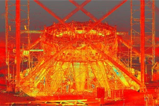 Una colorida imagen de escaneado 3D de nubes de puntos muestra el armazón de una gran estructura industrial en construcción en Texcoco para el proyecto NAICM, con tonos rojos, amarillos y naranjas brillantes que resaltan vigas y andamios.