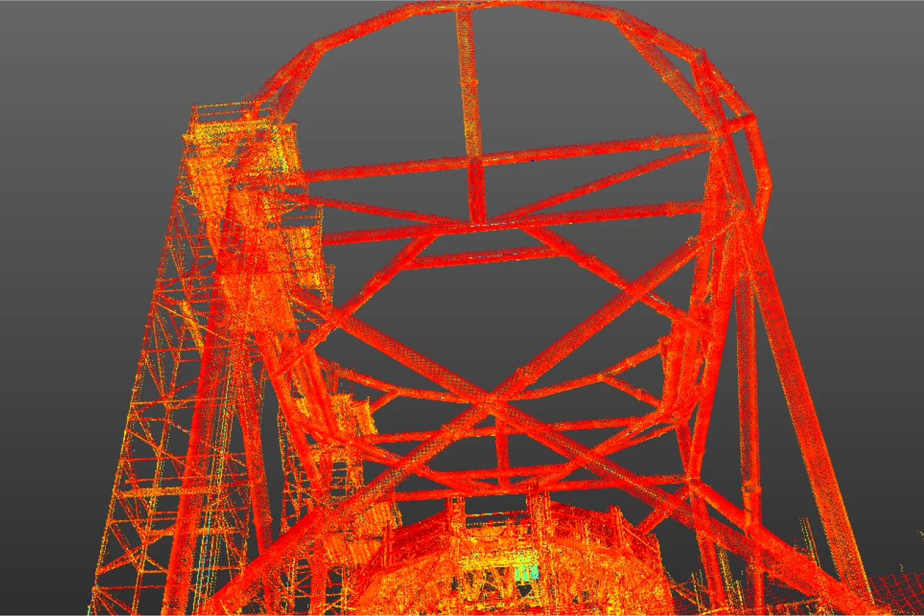 Una nube de puntos digital muestra una gran estructura geométrica de acero con una parte superior circular, vista desde abajo sobre un fondo gris. La estructura inspirada en el NAICM se representa en tonos rojos, naranjas y amarillos.