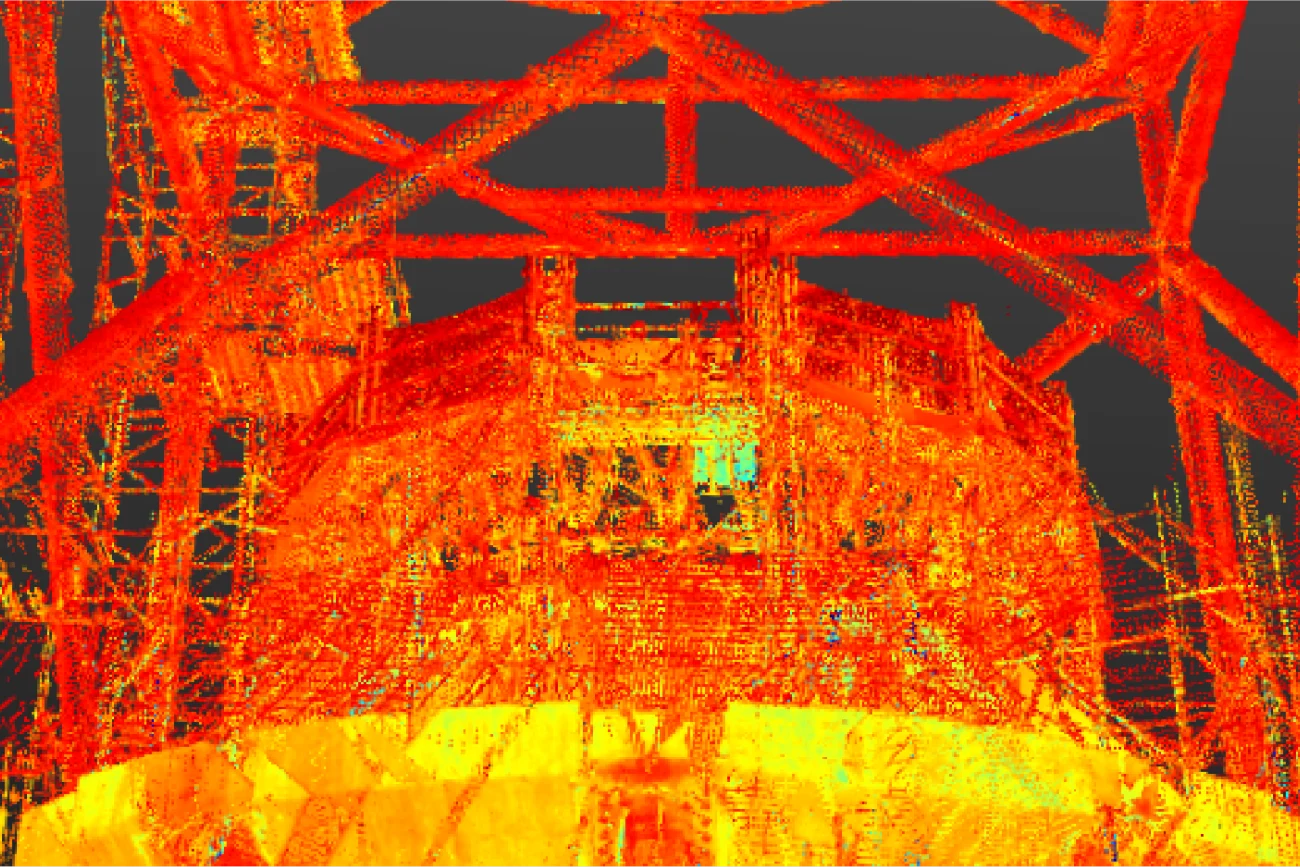 Nube digital de puntos de una gran estructura industrial -posiblemente inspirada en el NAICM Texcoco- en la que predominan los tonos amarillos, naranjas y rojos, con vigas que se cruzan y formas geométricas sobre un fondo oscuro.