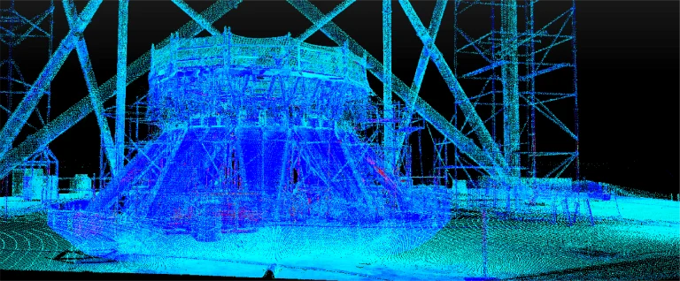 Nube de puntos en 3D de una gran estructura industrial, posiblemente parte del sitio del NAICM Texcoco, mostrada en diferentes tonos de puntos azules, verdes y rojos sobre un fondo oscuro