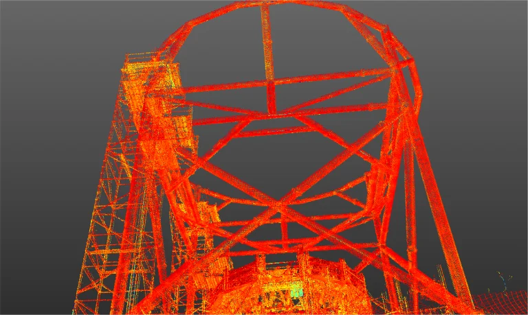 Una nube de puntos digital muestra parte de la estructura metálica industrial del NAICM en naranja y amarillo, vista desde abajo sobre un fondo gris, evocando la escala del ambicioso proyecto aeroportuario de Texcoco