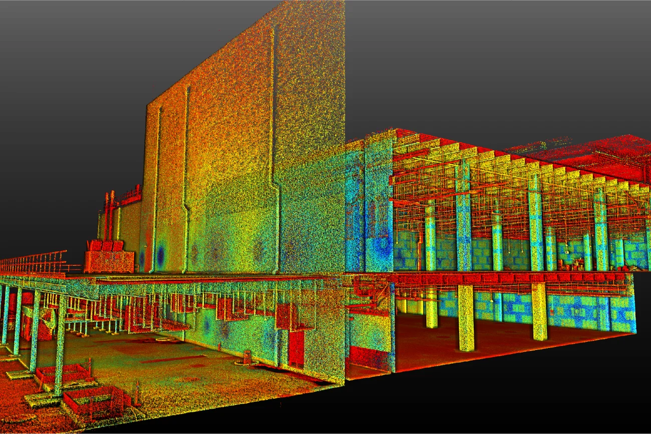 Un escaneo de nube de puntos 3D del interior y el exterior de un edificio grande, como un centro de datos EQUINIX, revela detalles estructurales con puntos de colores del rojo al azul que indican diferentes alturas o valores de medición, sobre un fondo oscuro.