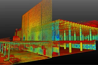 Un escaneo de nube de puntos 3D del interior y el exterior de un edificio grande, como un centro de datos EQUINIX, revela detalles estructurales con puntos de colores del rojo al azul que indican diferentes alturas o valores de medición, sobre un fondo oscuro.