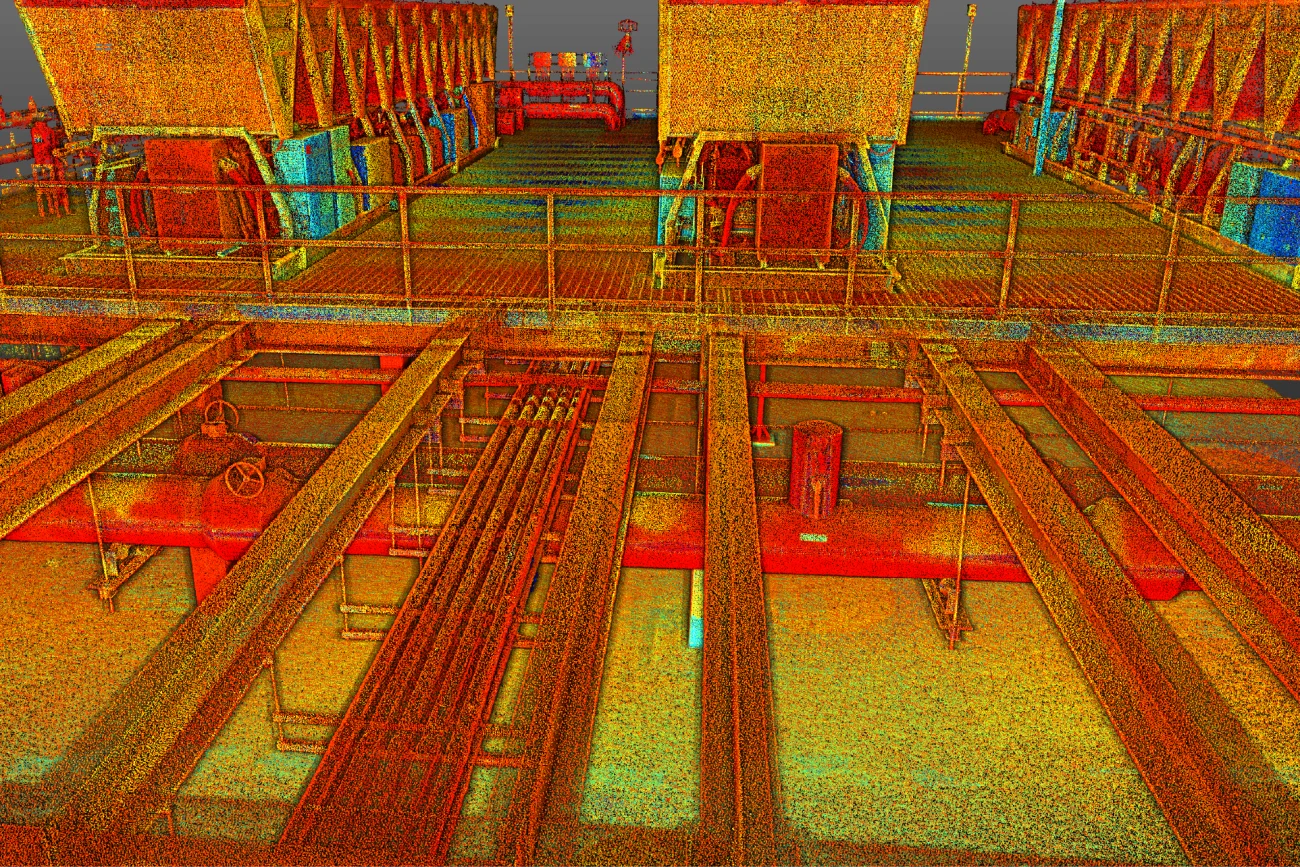 Un escaneo 3D de nube de puntos de una instalación industrial, capturado por BOVIS, muestra pasarelas, barandillas, maquinaria pesada, tuberías y equipos. Los colores representan la profundidad y los detalles de la superficie en intensos tonos rojo, amarillo, verde y azul.