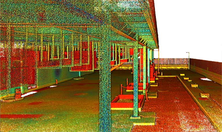 Una colorida nube de puntos en 3D del exterior de un edificio, con columnas de soporte, ventanas y plazas de aparcamiento en un emplazamiento de EQUINIX. Creada con tecnología LiDAR, la imagen está densamente moteada con puntos rojos, verdes y amarillos