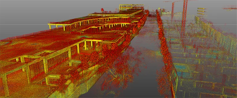 Una colorida nube de puntos escaneada en 3D de un edificio parcialmente construido y sus alrededores, incluido el Centro Comercial Punto Sur, que muestra varios niveles estructurales, árboles y grúas de construcción desde una perspectiva elevada