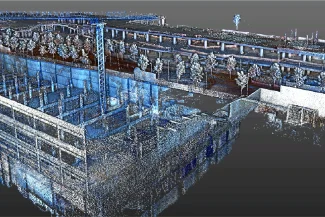 Una nube de puntos en 3D muestra parte de las obras del Centro Comercial Punto Sur con el armazón de un edificio, grúas y árboles cercanos, visualizados en partículas digitales azules y blancas.