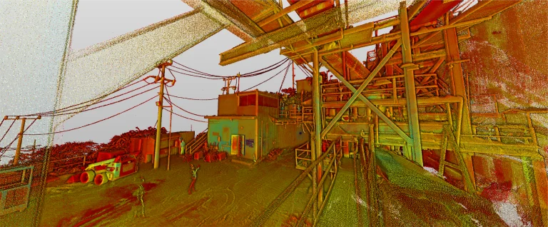 Una colorida representación en nube de puntos de una escena industrial al aire libre en Mina DIABRAS, con postes, cables, maquinaria y estructuras metálicas sobre un cielo nublado