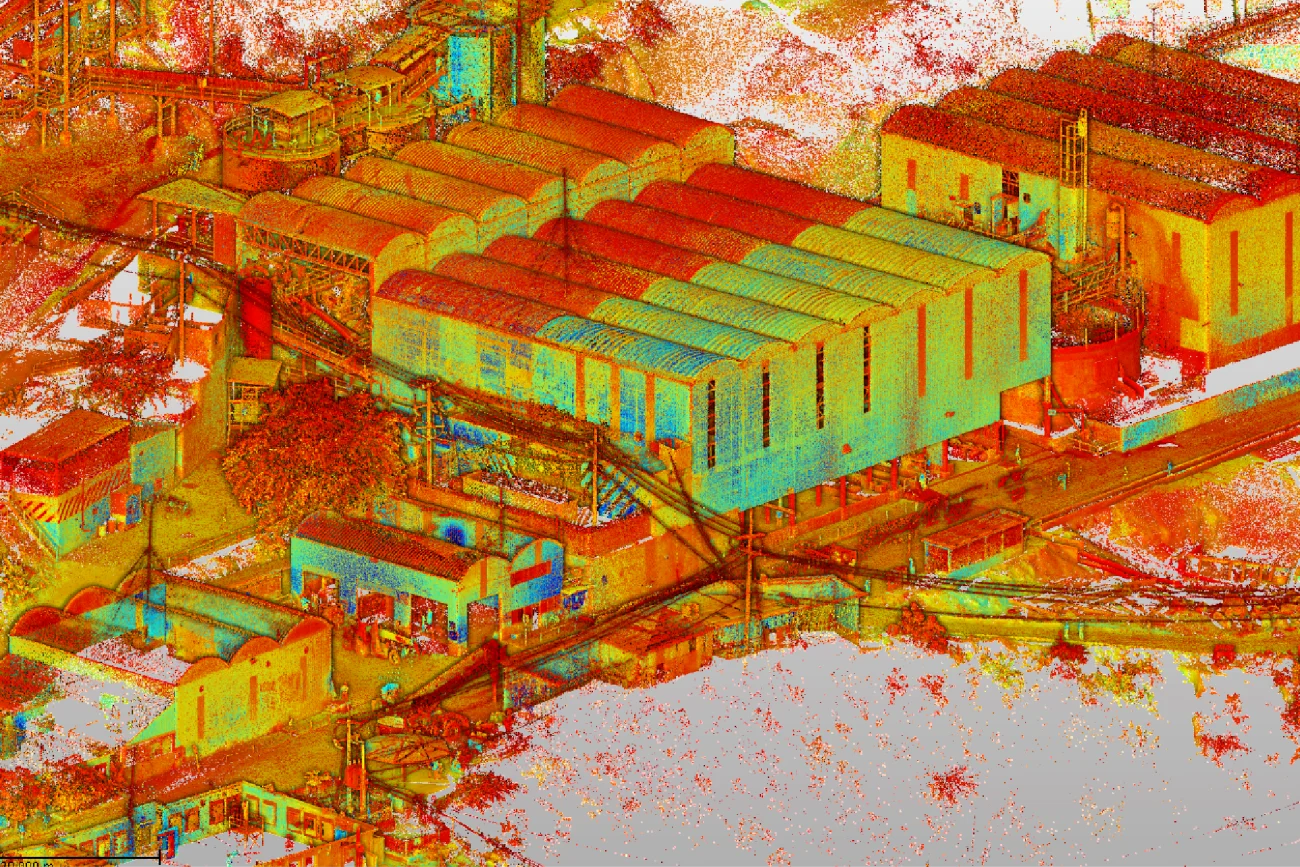 Una representación colorida y de alto contraste de una nube de puntos del complejo industrial Mina DIABRAS, que muestra grandes almacenes, edificios más pequeños, caminos y árboles dispersos en tonos brillantes de rojo, amarillo, naranja y verde.