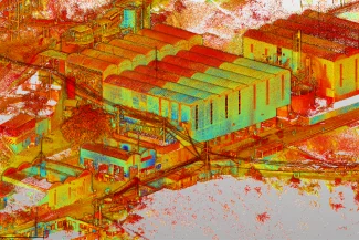 Una representación colorida y de alto contraste de una nube de puntos del complejo industrial Mina DIABRAS, que muestra grandes almacenes, edificios más pequeños, caminos y árboles dispersos en tonos brillantes de rojo, amarillo, naranja y verde.