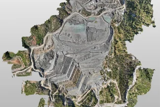 Vista aérea de la mina a cielo abierto Mina DIABRAS con niveles de excavación en terrazas, caminos sinuosos y vegetación circundante. Los edificios y las instalaciones de procesamiento se aprecian en la parte superior de la imagen.