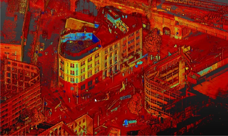 Una colorida nube de puntos escaneada en 3D de una zona urbana, creada con GGM 115 Londres BIM y escaneo láser, muestra edificios, calles y vehículos en vibrantes tonos rojos, naranjas y azules, como si se tratara de un mapa digital o una visualización LiDAR