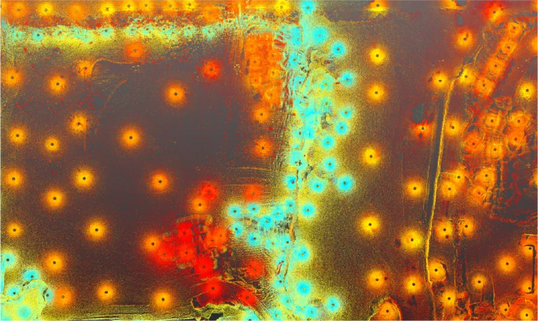 Vista aérea que muestra una cuadrícula de puntos rojos, naranjas y azules brillantes sobre un fondo oscuro texturizado, parecido a un mapa de calor o a las luces nocturnas de una ciudad, evocando la energía dinámica de una Planta Industrial Nissan con líneas y racimos formando patrones abstractos