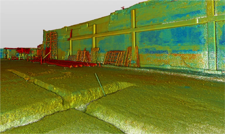 Colorido escaneo de nube de puntos 3D de un Escaneo Láser Coppel Culiacán muestra grandes muros, vigas estructurales, tuberías dispersas, andamios y suelo irregular agrietado. Los colores falsos resaltan las variaciones en la elevación de la superficie