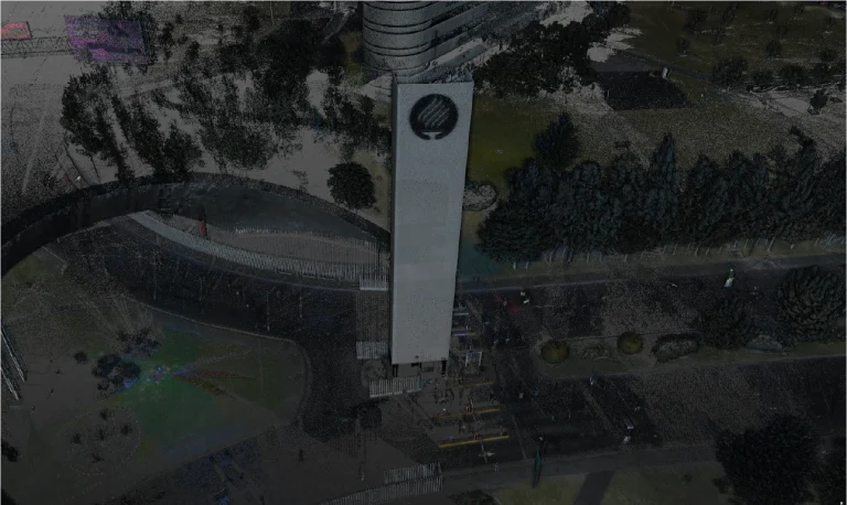 Nube de puntos torre blanca con un emblema redondo en blanco y negro en la parte superior se alza junto a una carretera curva y árboles del Tecnológico de Monterrey