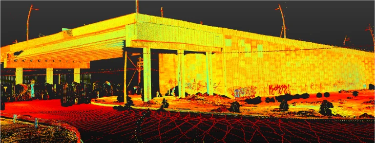 Una colorida nube de puntos LiDAR escaneada de un paso elevado de autopista en la intersección vial de las calles Lincoln y Kennedy por la noche, que muestra brillantes puntos amarillos, naranjas y rojos que forman la estructura y el terreno circundante, con altas columnas y una vegetación mínima visible