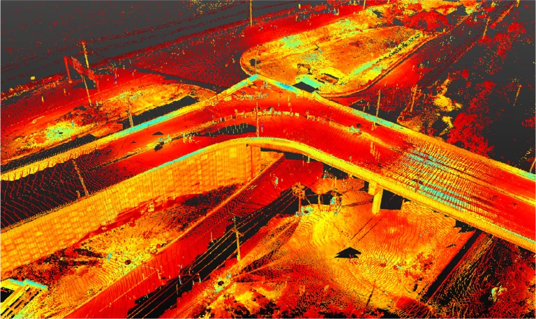 Una imagen de nube de puntos LiDAR que muestra una vista aérea del vial de intersección en las calles Kennedy y Lincoln, con carreteras, pasos elevados y terreno en tonos rojos, naranjas y amarillos para representar los datos de elevación