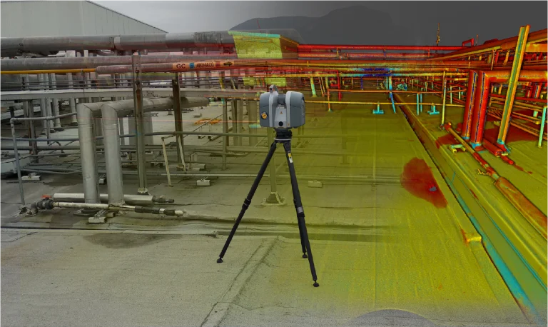 Un dispositivo de escaneado láser 3D montado sobre un trípode se encuentra en la Planta Industrial Sukarne, capturando un escaneado digital que superpone coloridos datos de nubes de puntos a imágenes de tuberías y equipos