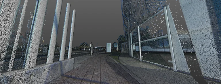 Vista en nube de puntos de una acera urbana pavimentada junto a postes verticales y un edificio cercado de cristal en el Tecnológico de Monterrey en Pachuca, con árboles y elementos de la calle visibles en la distancia