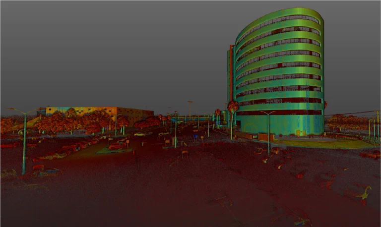 Colorido escaneado lidar del Tecnológico de Monterrey, Querétaro: un edificio curvo de varios pisos con ventanas a la derecha, un gran edificio rectangular a la izquierda y un aparcamiento con coches y postes de la luz en primer plano bajo un cielo gris