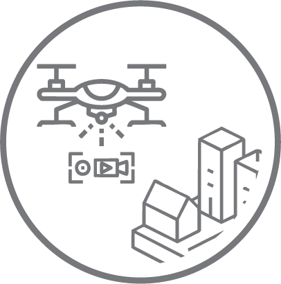 Un dibujo lineal de un dron volando sobre el símbolo de una cámara, con edificios y casas debajo todo ello dentro de un borde circular.