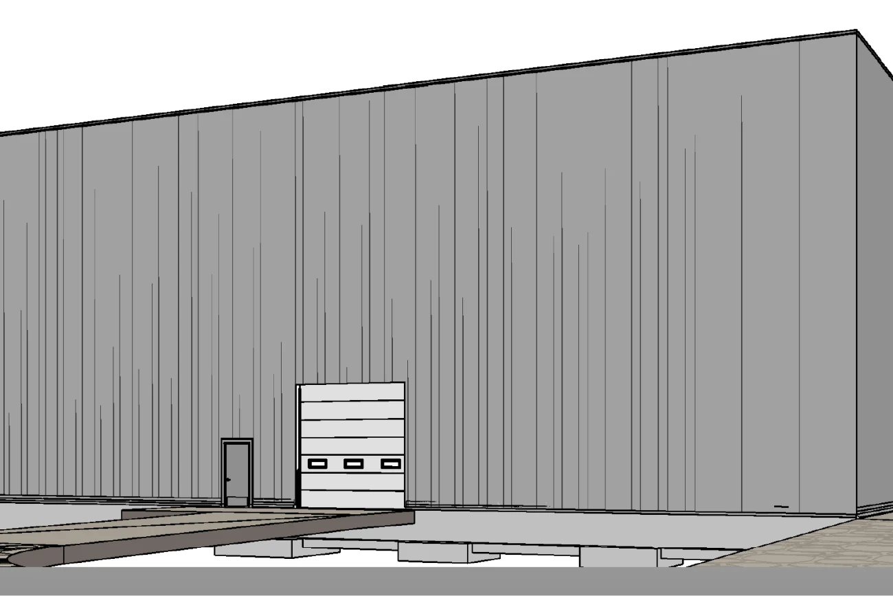 A large, rectangular, gray industrial building at the BMW Industrial Plant, with a tall garage door and a smaller entrance door. The paved floor in front features exposed concrete and visible construction elements.