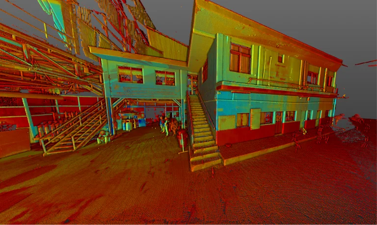 Una nube de puntos 3D coloreada del Ingenio Azucarero Tamazula en Jalisco muestra un edificio de dos plantas con escaleras, ventanas y personas cerca. Alrededor del lugar también hay estructuras metálicas y barriles utilizados en la producción de azúcar