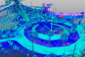 Imagen de nube de puntos colorida de un parque circular cerca del Aeropuerto Internacional de CDMX, con palmeras, senderos y un monumento central. Vista desde arriba, los gradientes de azul, verde y rosa representan la elevación o la profundidad.