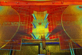 Nube de puntos de estructura industrial en el aeropuerto de Guadalajara, con paredes curvas, columnas cilíndricas y una escalera central, representada en un vibrante estilo puntillista con tonos rojos, amarillos, naranjas y azules.