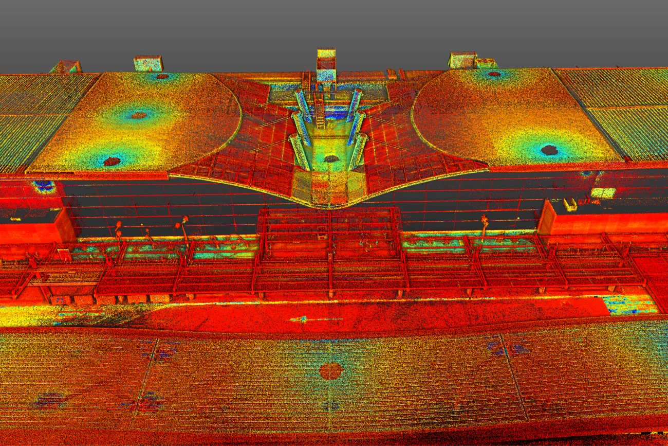Una colorida nube de puntos LiDAR escaneada de la azotea del Aeropuerto Internacional de Guadalajara, que muestra varias estructuras y características redondas, con puntos de datos en rojo, amarillo, verde y azul para indicar las diferencias de elevación.