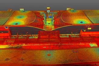Una colorida nube de puntos LiDAR escaneada de la azotea del Aeropuerto Internacional de Guadalajara, que muestra varias estructuras y características redondas, con puntos de datos en rojo, amarillo, verde y azul para indicar las diferencias de elevación.