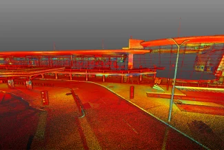 Un colorido escaneado láser 3D del Aeropuerto Internacional de Guadalajara muestra los edificios de la terminal, las farolas, las señales y la calzada circundante en tonos rojos, naranjas, amarillos y verdes sobre un fondo gris.