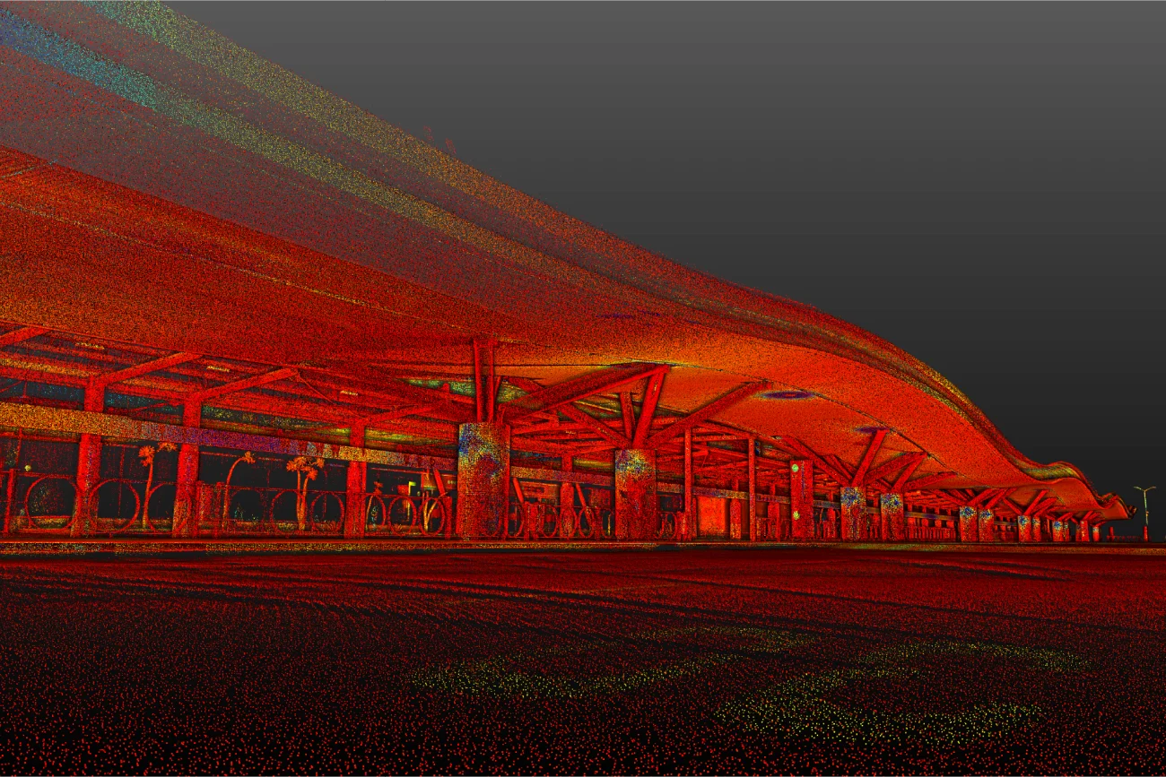 Nube de puntos de un andén de estación vacío y moderno por la noche, con tonos rojos y naranjas brillantes y un tejado curvado que recuerda a la elegante arquitectura del Aeropuerto Internacional de Guadalajara.