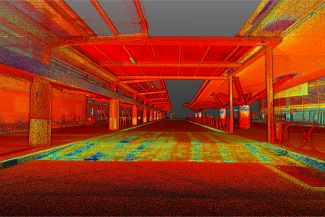 Nube de puntos de un pasillo cubierto vacío en el aeropuerto de Guadalajara, con tonos rojos, naranjas y amarillos brillantes que resaltan las columnas, el techo y el suelo en un estilizado patrón puntillista.