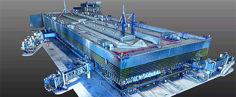 Un gran edificio industrial de planta rectangular con varias tuberías, plataformas y estructuras en el tejado y los laterales se alza sobre un fondo gris liso que recuerda a las modernas instalaciones del Aeropuerto Internacional de Tijuana