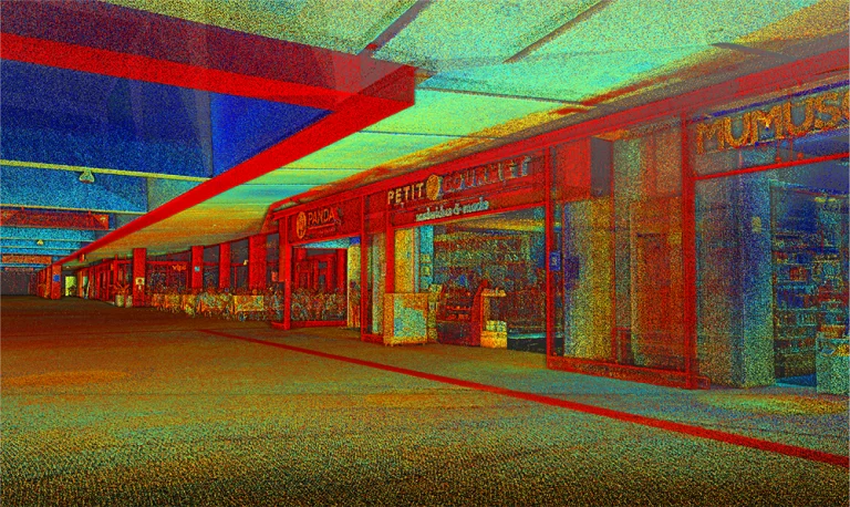 Nube de puntos de un pasillo de un centro comercial con escaparates, entre los que se encuentran carteles de Petite Brulerie y Tabac, evoca el animado ambiente que se respira en las tiendas del Aeropuerto Internacional de Tijuana. La escena está cubierta por un filtro granulado multicolor