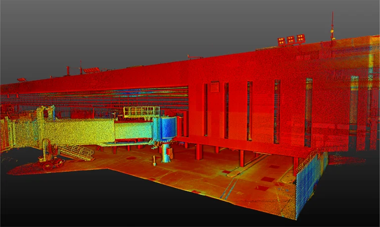 Nube de puntos 3D codificada por colores del exterior del Aeropuerto Internacional de Tijuana, que muestra detalles estructurales como las ventanas, el puente del reactor y el pavimento, con tonos rojos, naranjas, amarillos y verdes que indican la profundidad y los contornos de la superficie