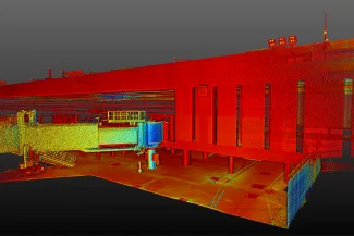 Una colorida nube de puntos escaneada en 3D de la terminal del Aeropuerto Internacional de Tijuana muestra un puente a reacción y la fachada del edificio en tonos rojos, amarillos y verdes sobre un fondo oscuro.