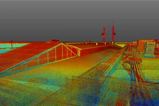 Colorido escaneado láser 3D de un tejado plano en el Aeropuerto Internacional de Tijuana, con varias estructuras, respiraderos y barandillas, mostrado en un estilo de nube de puntos sobre un fondo de cielo gris.