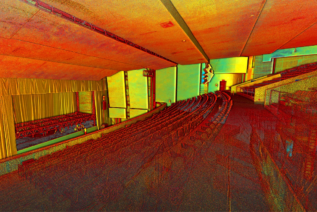 Nube de puntos del Auditorio Blackberry vacío muestra filas de asientos frente a un escenario con telones. Los asientos, las paredes y el techo muestran un vibrante espectro de tonos rojos, amarillos y verdes.