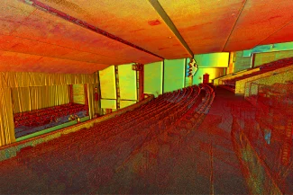 Nube de puntos del Auditorio Blackberry vacío muestra filas de asientos frente a un escenario con telones. Los asientos, las paredes y el techo muestran un vibrante espectro de tonos rojos, amarillos y verdes.