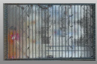 An aerial view of a rectangular enclosed area at the BMW Industrial Plant, with people walking across a floor covered in colorful dust and patches of black, orange, and white, creating a vivid, abstract pattern.