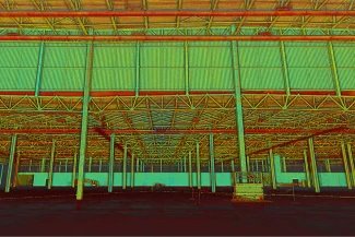 El interior de un almacén vacío de Planta Industrial BMW con vigas y columnas de acero a la vista, coloreado con filtros verdes, amarillos y rojos para conseguir un efecto surrealista de alto contraste. El espacio parece amplio y vacío.