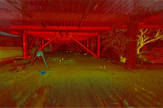 Una estructura abierta, de estilo industrial, con vigas de acero rojo y tejado parcialmente abierto, domina frondosos árboles y arbustos bañados en luz dorada: una vívida instantánea de vida urbana dentro del desarrollo de Corteza Residencial. El suelo está salpicado de objetos diversos.