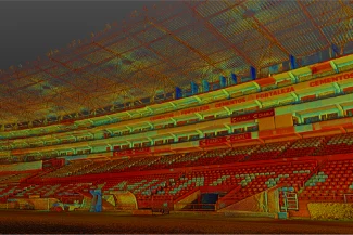 The large, empty Nou Camp Stadium features red and white seats, covered stands, and advertising banners. The lush green field appears below, while stadium lights hang from the ceiling above.