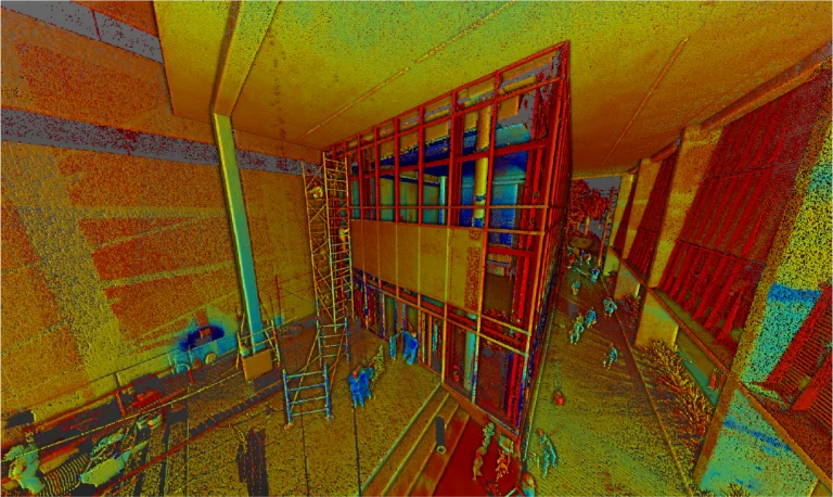 Una colorida nube de puntos escaneada en 3D del gran espacio interior del Centro Médico ISSSTE León, con techos altos, andamios, vigas estructurales y varias personas caminando o de pie por la zona