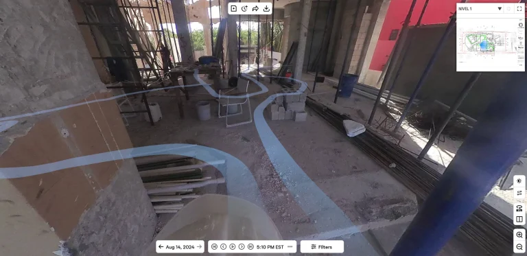 Una obra con materiales dispersos, varillas metálicas, cubos, andamios y líneas azules superpuestas sobre el suelo muestra una detallada captura de la realidad. Un mapa e información del proyecto aparecen en la esquina superior derecha; la foto tiene fecha de agosto de 2024.