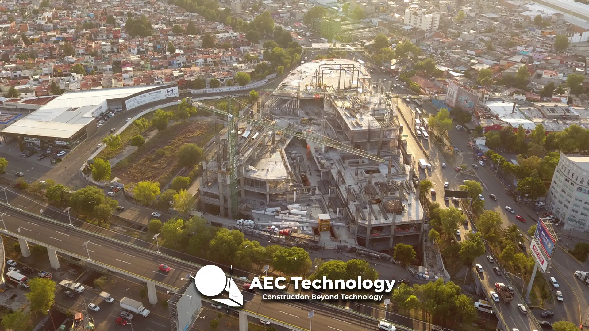 Vista aérea de la obra del Centro Comercial Sentura Tlalnepantla en medio de un paisaje urbano, rodeado de vialidades y edificios residenciales, con el logotipo y texto AEC Technology Construction Beyond Technology en la parte inferior.